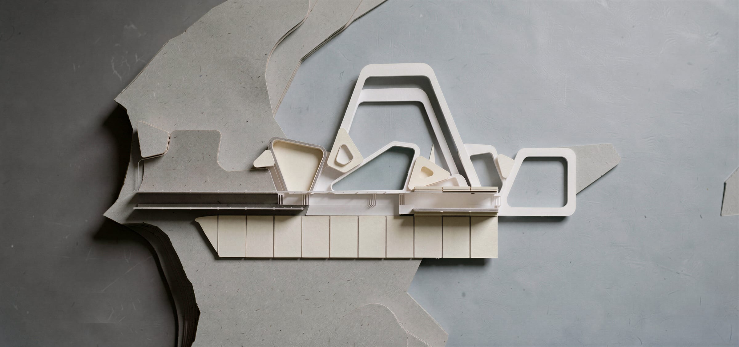 Model of the building on the shelf between the mountain contours and the water, seen from above